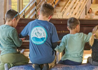 Four Children at Camp By The Sea playing the piano at Slough Farm