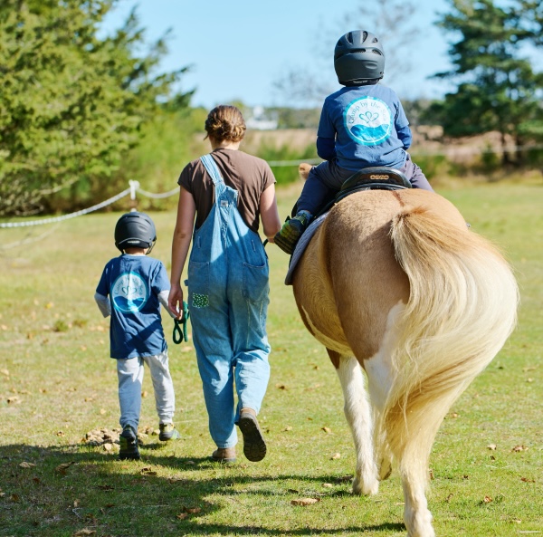 Campers walking with volunteer and riding a horse