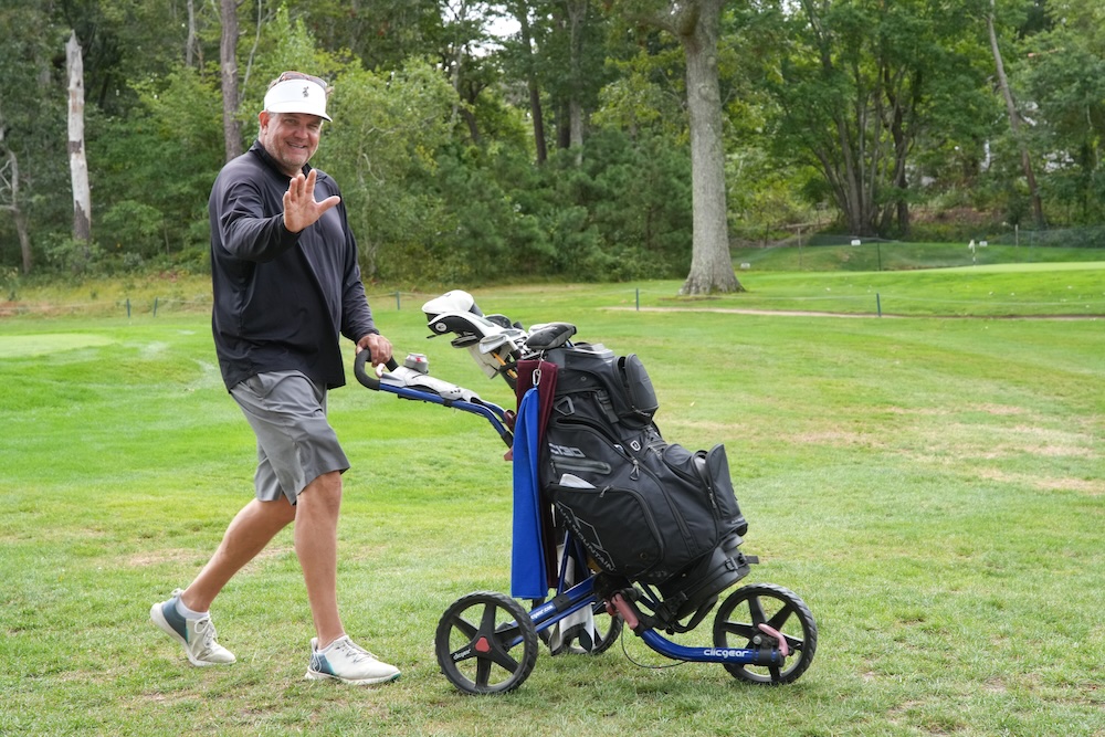 Golfer walking with his clubs and waving